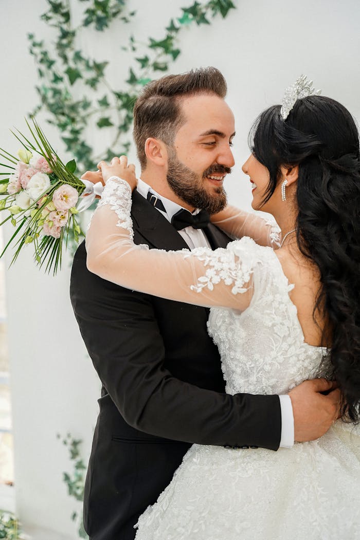 Smiling bride and groom embrace lovingly in elegant wedding attire.